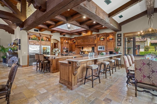 6314 El Apajo, Rancho Santa Fe, CA 92067 - kitchen with stainless steel appliances, stone tile floors, a breakfast bar, arched walkways, and recessed lighting