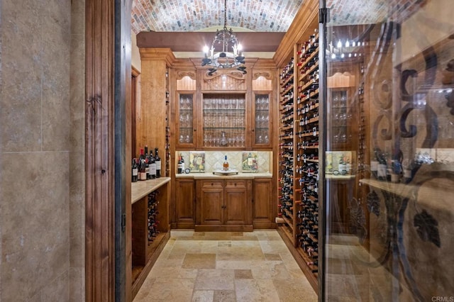 6314 El Apajo, Rancho Santa Fe, CA 92067 - wine room with stone tile flooring, a chandelier, vaulted ceiling, and brick ceiling