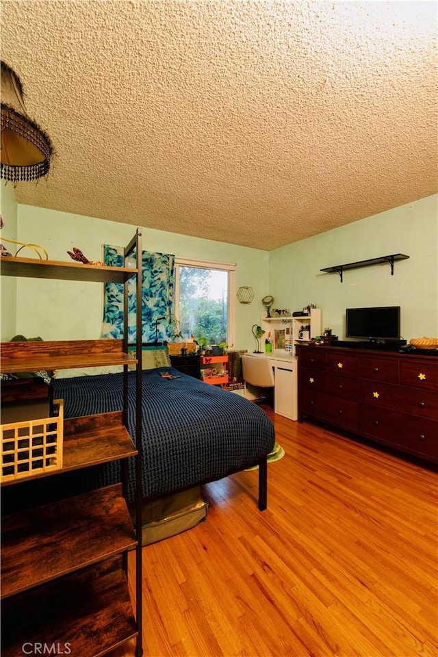 bedroom with a textured ceiling and wood finished floors