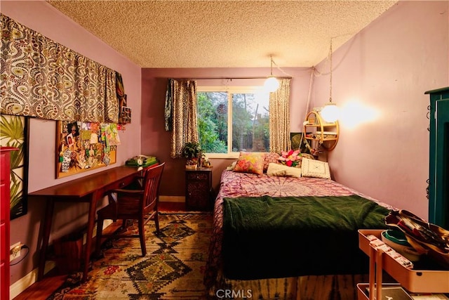 bedroom featuring baseboards, a textured ceiling, and wood finished floors