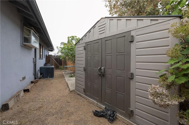 view of shed featuring fence and central AC unit