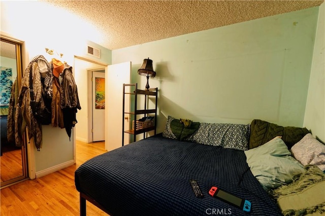bedroom featuring a textured ceiling, visible vents, and light wood-type flooring
