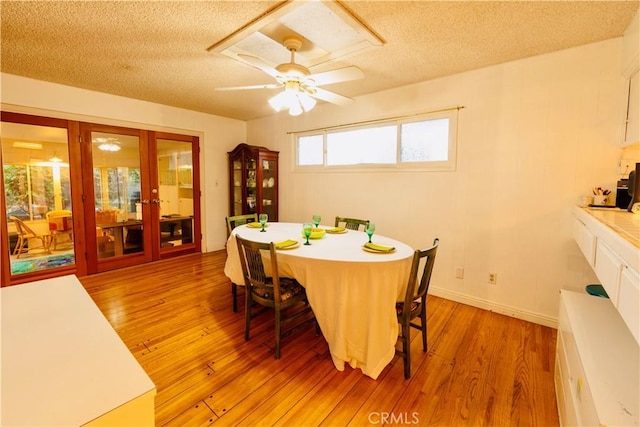 dining room with french doors, a textured ceiling, light wood-style floors, and a ceiling fan
