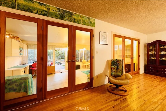 doorway with french doors, a textured ceiling, and wood-type flooring