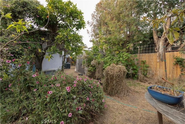 view of yard featuring a storage unit, an outdoor structure, and fence