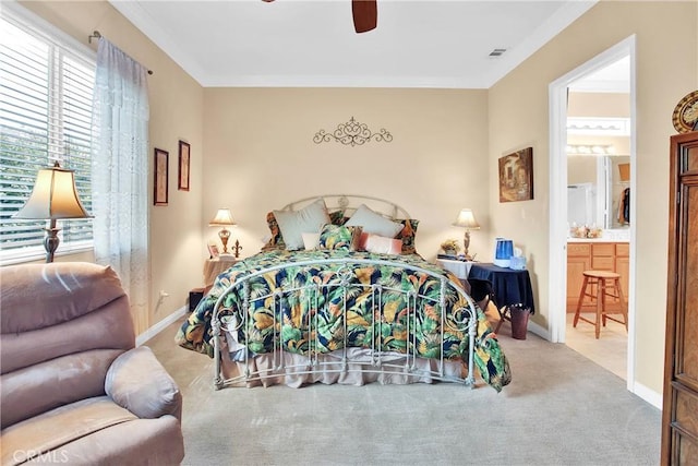 carpeted bedroom featuring visible vents, a ceiling fan, crown molding, baseboards, and ensuite bathroom