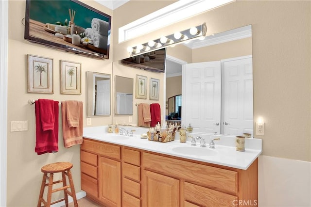 bathroom featuring double vanity, ornamental molding, and a sink