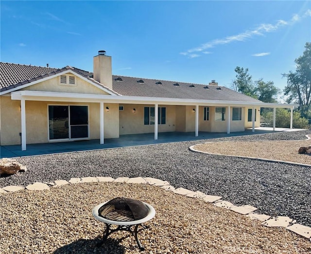 19640 Yanan Rd, Apple Valley, CA 92307 - back of property featuring a chimney, stucco siding, an outdoor fire pit, and a patio
