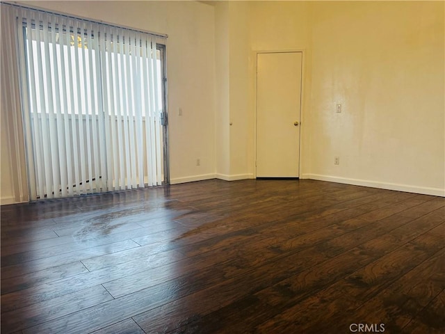 unfurnished room with baseboards and dark wood-style floors