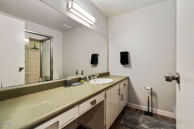 bathroom with vanity, toilet, baseboards, wood finished floors, and an enclosed shower