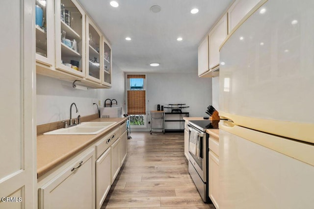 kitchen featuring light wood-type flooring, a sink, freestanding refrigerator, stainless steel electric stove, and recessed lighting