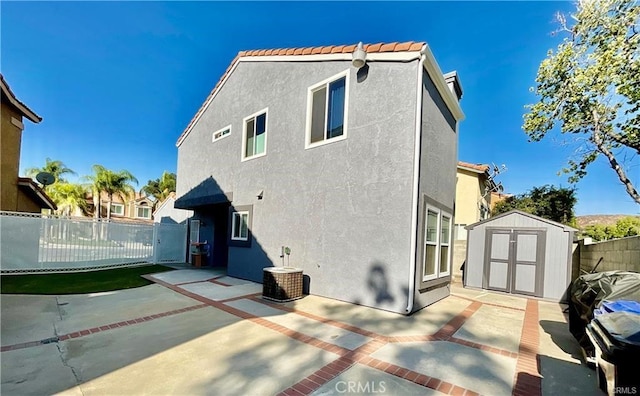 14679 Cinnamon Dr, Fontana, CA 92337 - rear view of property featuring a storage shed, stucco siding, a patio, fence, and central AC unit