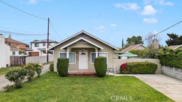 bungalow-style house with stucco siding, a front lawn, and a fenced front yard