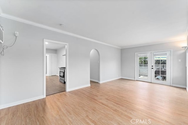 unfurnished living room with baseboards, arched walkways, crown molding, and light wood-style flooring