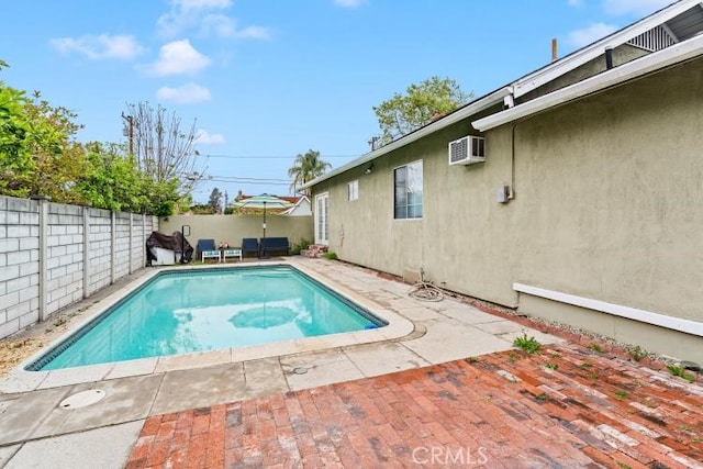 view of pool with a patio area, a fenced in pool, a wall mounted AC, and a fenced backyard