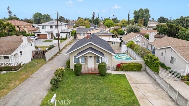 view of front of house featuring concrete driveway, a front lawn, fence, and a residential view