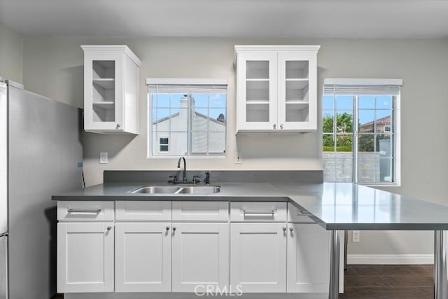 kitchen featuring white cabinets, glass insert cabinets, freestanding refrigerator, and a sink