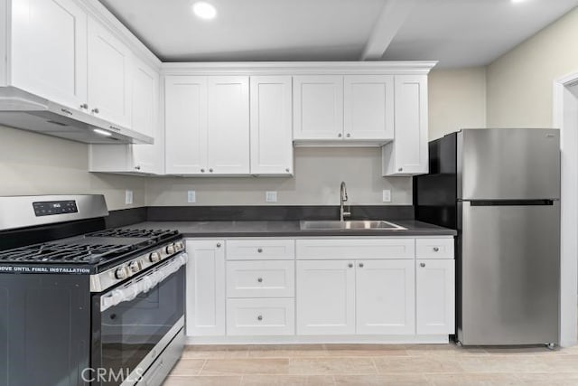 kitchen with dark countertops, a sink, appliances with stainless steel finishes, white cabinets, and under cabinet range hood