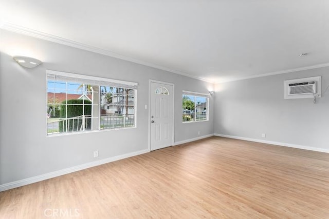 interior space featuring baseboards, crown molding, light wood finished floors, and a wall unit AC