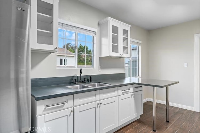 kitchen with dark countertops, freestanding refrigerator, a sink, and dark wood-style floors