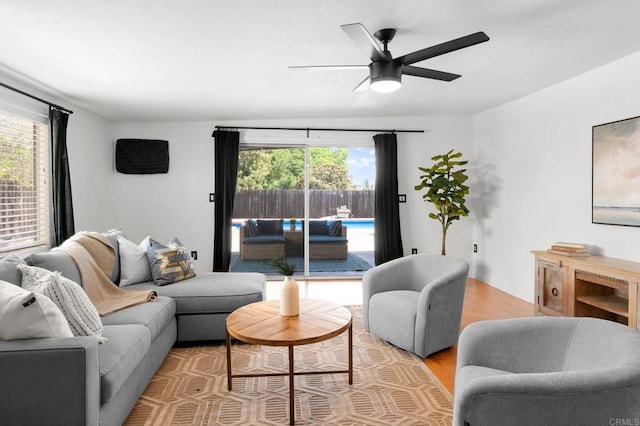living room featuring ceiling fan, light wood-type flooring, and a healthy amount of sunlight