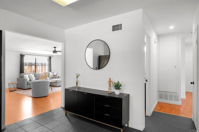 hallway featuring baseboards, dark tile patterned floors, visible vents, and recessed lighting