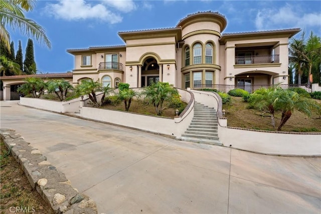 mediterranean / spanish home featuring stucco siding, a tile roof, and a balcony