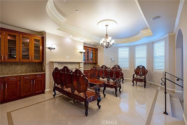 dining space featuring a notable chandelier, baseboards, crown molding, and a tray ceiling