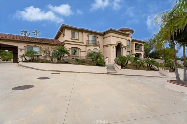 mediterranean / spanish-style home with stucco siding, a tiled roof, and a balcony