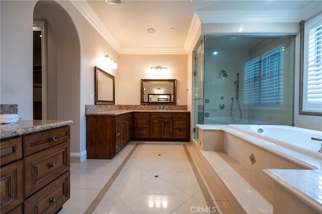bathroom with a garden tub, tile patterned floors, a tile shower, ornamental molding, and two vanities