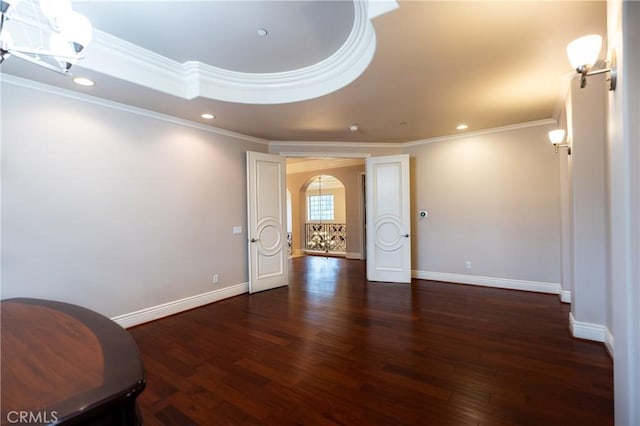 empty room with arched walkways, wood finished floors, baseboards, and ornamental molding
