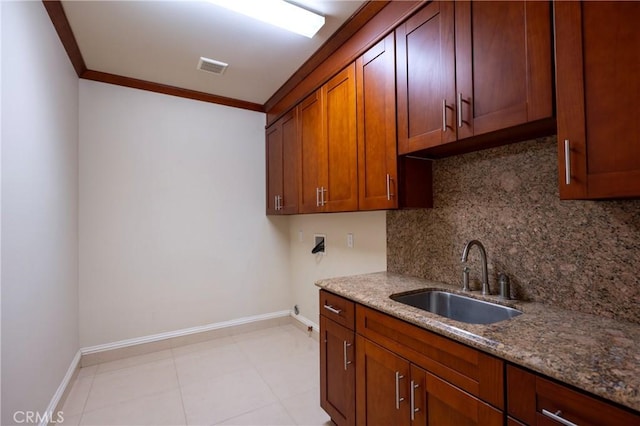 kitchen with crown molding, tasteful backsplash, a sink, baseboards, and visible vents