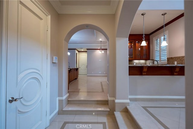 staircase with arched walkways, ornamental molding, tile patterned floors, and baseboards