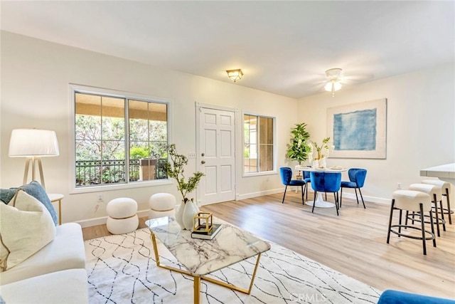 living room featuring ceiling fan, baseboards, and wood finished floors