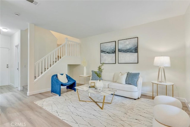 living area with stairway, visible vents, baseboards, and wood finished floors