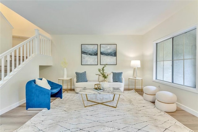 living area featuring baseboards, wood finished floors, and stairs
