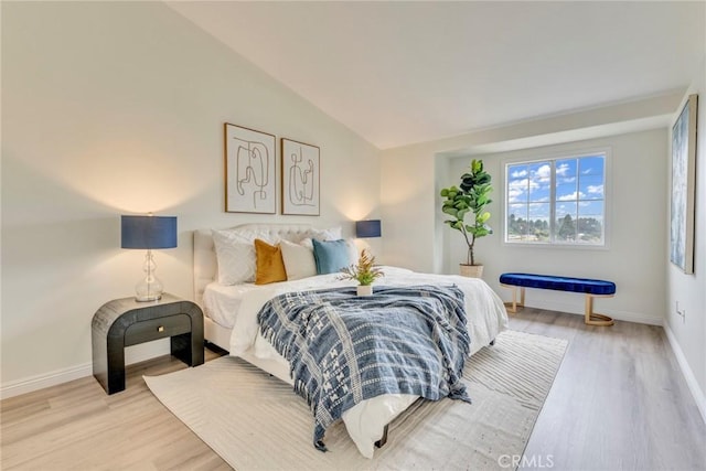 bedroom featuring vaulted ceiling, light wood-type flooring, and baseboards