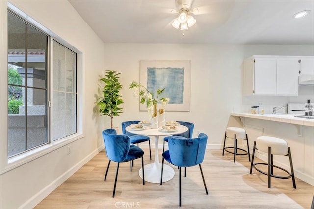 dining space featuring light wood-style flooring, baseboards, and ceiling fan