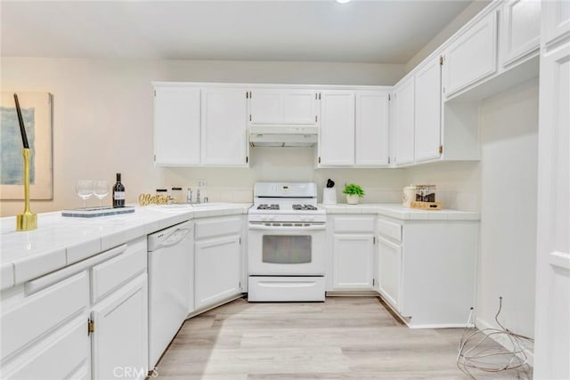 kitchen with white cabinets, under cabinet range hood, tile counters, and white appliances