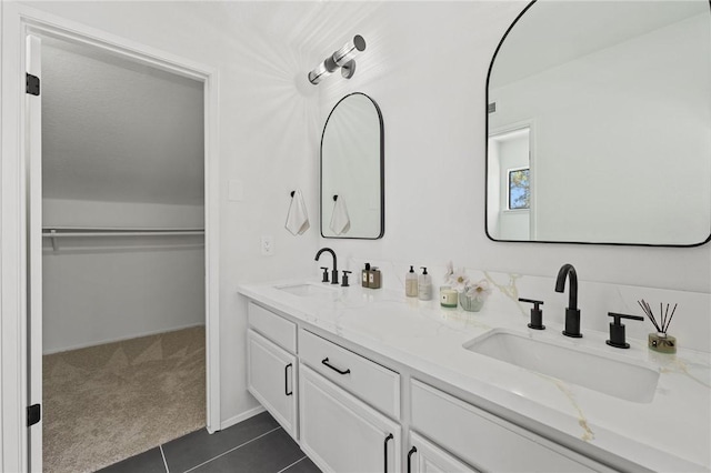 full bath featuring a spacious closet, tile patterned floors, double vanity, and a sink