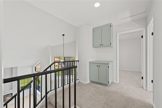 hallway with a healthy amount of sunlight, light colored carpet, baseboards, and an upstairs landing