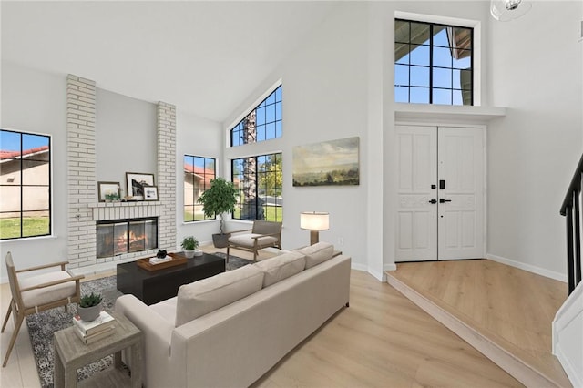 living room featuring high vaulted ceiling, a fireplace, baseboards, and wood finished floors