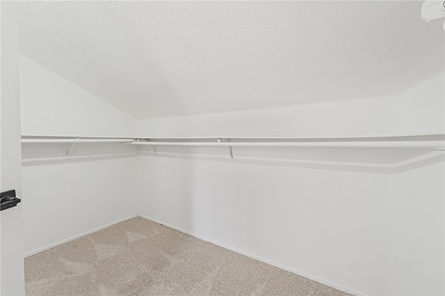 walk in closet with carpet and lofted ceiling