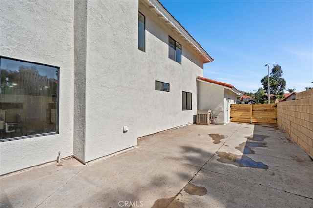 view of home's exterior featuring central air condition unit, stucco siding, a patio area, a tiled roof, and fence