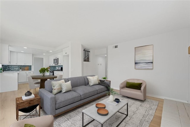 living area featuring baseboards, light wood finished floors, and recessed lighting