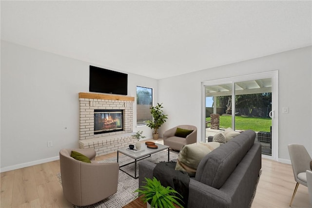 living room featuring light wood-style flooring, baseboards, and a fireplace
