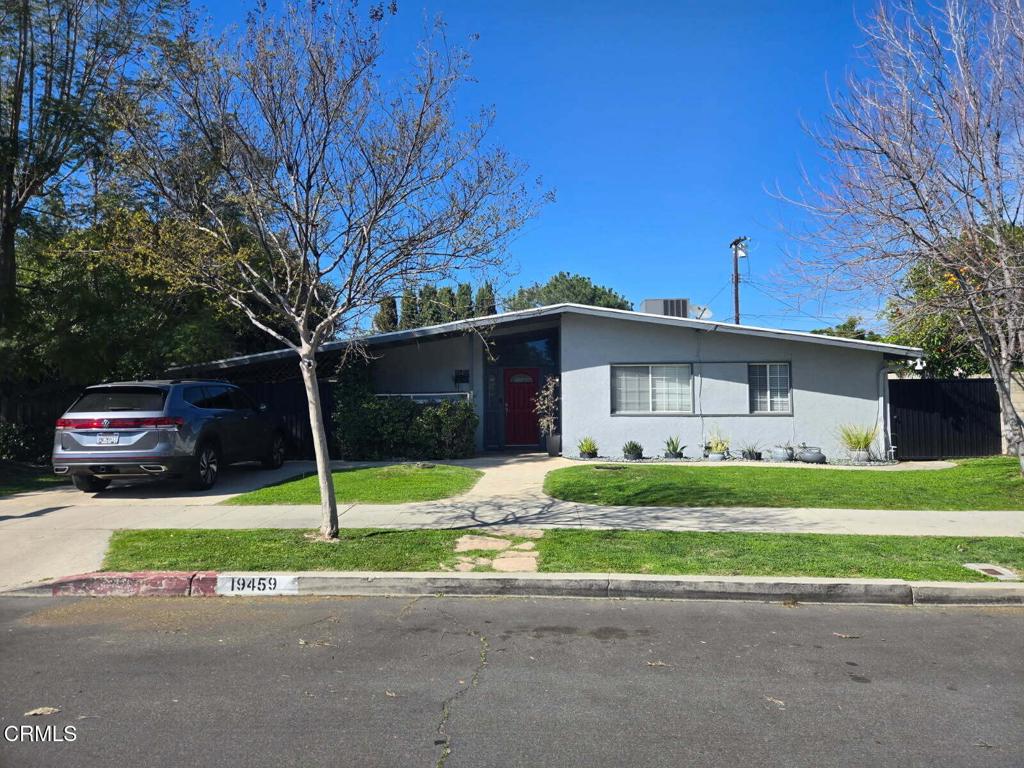 view of front facade featuring stucco siding, driveway, fence, and a front yard