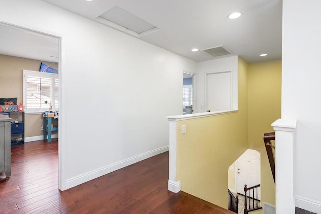 hallway featuring attic access, wood finished floors, baseboards, and an upstairs landing