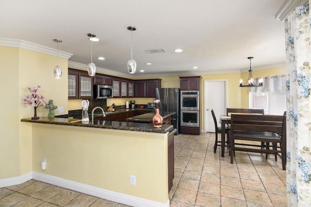 kitchen with stone tile floors, baseboards, appliances with stainless steel finishes, and crown molding