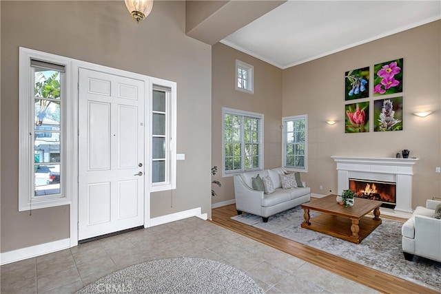 24932 Normans Way, Calabasas, CA 91302 - entryway with tile patterned flooring, a high ceiling, crown molding, and a lit fireplace